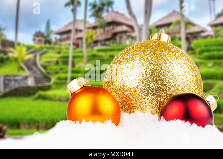 Thema Weihnachten mit balinesischen Dorf unscharfen Hintergrund, balinesische Architektur in den Hintergrund und die drei bunten Weihnachtskugeln in der Front Stockfoto