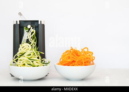Spiralizing Zucchini und Karotten vor einem weißen Hintergrund Stockfoto