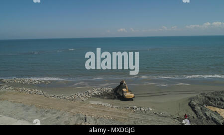 Bau der Küsten schützende Strukturen, Aufbau von Strukturen gegen die Wellen im Meer am Strand von Lingayen zu schützen. Luftaufnahme Baumaschinen am Meer, Strand, Bau von Kai. Philippinen, Luzon Stockfoto