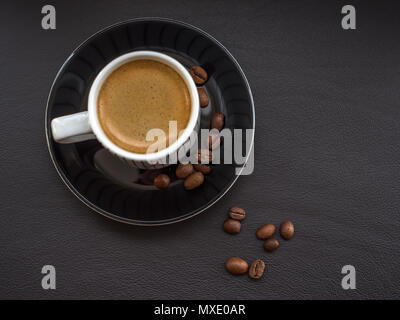 Kaffee auf dunklem Leder Oberfläche mit Kaffeebohnen Stockfoto