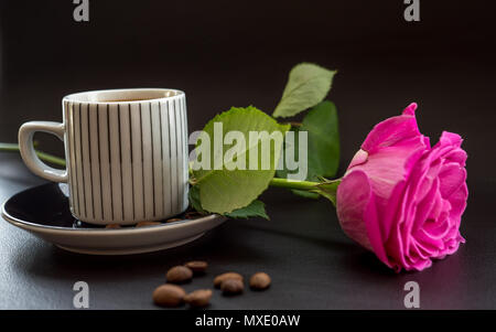 Kaffee mit rosa Rose auf dunklem Leder Oberfläche mit Kaffeebohnen Stockfoto