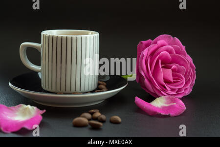 Kaffee mit rosa Rose auf dunklem Leder Oberfläche mit Kaffeebohnen Stockfoto