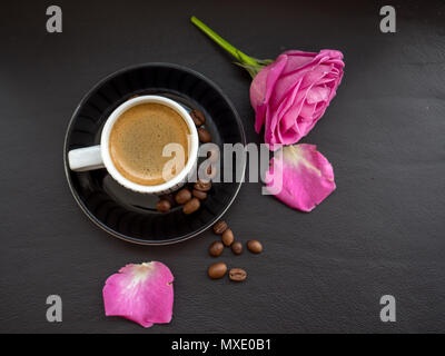 Kaffee mit rosa Rose auf dunklem Leder Oberfläche mit Kaffeebohnen Stockfoto