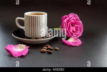 Kaffee mit rosa Rose auf dunklem Leder Oberfläche mit Kaffeebohnen Stockfoto