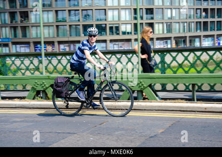 Ein Mann reitet hi Fahrrad auf die Hammersmith Bridge in London. Stockfoto