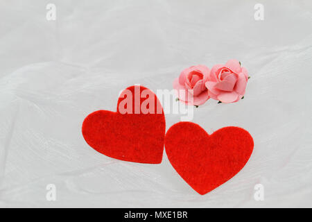 Zwei rote Herzen und zwei Rosa wenig Papier Rosen auf Weiß Textil mit Platz kopieren Stockfoto