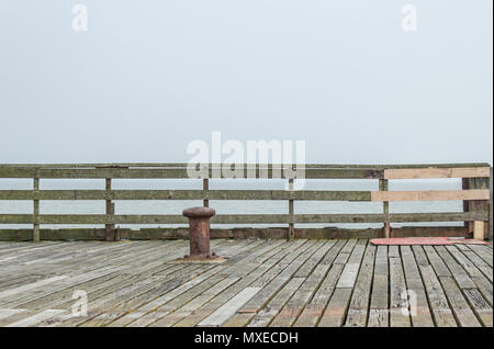 Rostige alte Poller zum Binden die Boote am Ende der Pier mit Blick auf das Meer an einem heißen Sommertag und Diesig Stockfoto