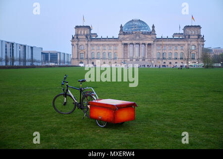 Berlin, Deutschland - 14 April 2018: Fahrrad mit Red Box auf dem Anhänger auf der grünen Wiese vor dem Reichstag mit wenige Touristen Stockfoto