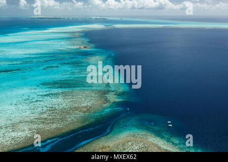 Blick aus der Vogelperspektive auf das große, weitläufige Barriereriff und das Kanalsystem um ein Korallenatoll Stockfoto