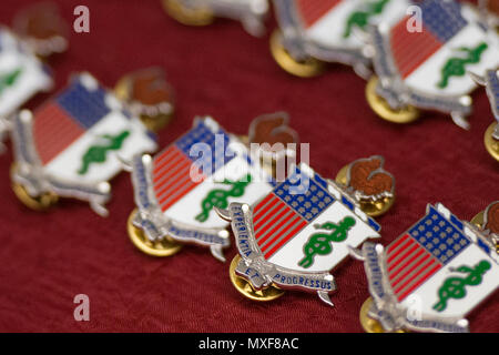 U.S. Army Medical Corps Regimental Wappen lag auf dem Tisch vor einem Zahnarzthelfer Abschlussfeier 2. Mai 2017, in der Medizinischen Ausbildung Campus, Joint Base San Antonio Fort Sam Houston, Texas. METC sorgt für Studenten der formalen Bildung und Berufsbildung, die sie in Eintrag entwickelt Ebene Zahnarzthelfer innerhalb fester und einsetzbaren medizinischen Einrichtungen zur Verfügung gestellt werden. Stockfoto