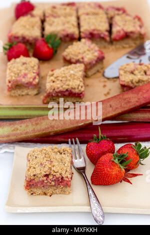 Gesunde Scheiben rot Sommer Früchte Bars serviert auf einem handgefertigte Keramik Teller. Ein köstliches, frisch gebackene Desserts mit Erdbeeren und Rhabarber. Stockfoto