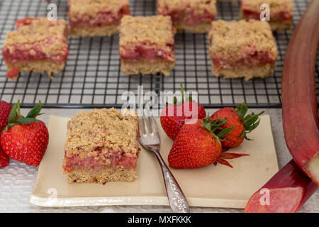 Gesunde Scheiben rot Sommer Früchte Bars serviert auf einem handgefertigte Keramik Teller. Ein köstliches, frisch gebackene Desserts mit Erdbeeren und Rhabarber. Stockfoto