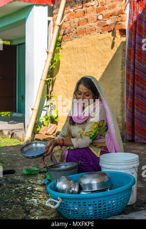 Eine Frau in einer traditionellen indischen Kleid wäscht Geschirr vor ihrem Haus auf dem Land. Indien Juli 2015 Stockfoto