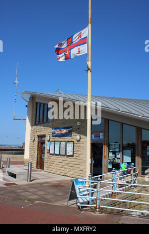 Ansicht der RNLI Flagge zum halben Flying-Mast am Royal National Lifeboat Institution Geschenk Shop im Hovercraft Station an der Promenade Morecambe, Lancashire, U. K. Stockfoto