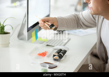 Nahaufnahme der männlichen Mitarbeiter genießen Sie Sushi am Arbeitsplatz Stockfoto