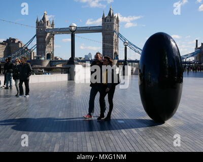 Touristen machen einen Spaziergang in der Nähe der Tower Bridge an einem sonnigen Tag in London, England. Stockfoto