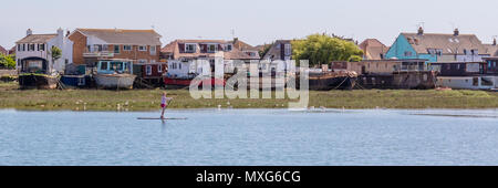 Shoreham-By-Sea; 3. Juni 2018; Panorama der Weibchen auf ein Paddle Board vorbei Hausboote am Flussufer Stockfoto