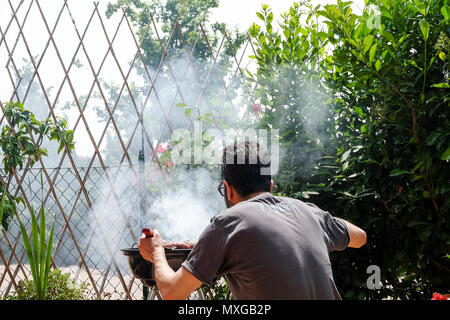 Einen sonnigen Tag im Garten, das Feuer im Grill und dann grillen von Fleisch mit Freunden Stockfoto