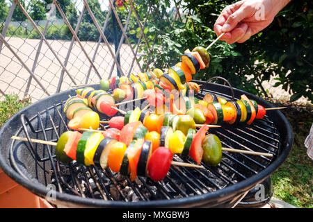 Kochen und Grillen Gemüse - Zucchini Tomaten und pepeer-Spieße auf dem Grill draußen ein sonniges entspanntes Wochenende Stockfoto