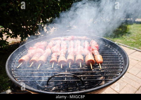 Einen sonnigen Tag im Garten, das Feuer im Grill und dann grillen Fleischspieße mit Freunden Stockfoto