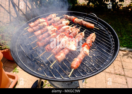 Einen sonnigen Tag im Garten, das Feuer im Grill und dann grillen Fleischspieße mit Freunden Stockfoto