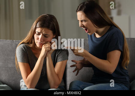 Wütende Frau schimpfen Sie traurig Freund sitzen auf einer Couch im Wohnzimmer zu Hause Stockfoto