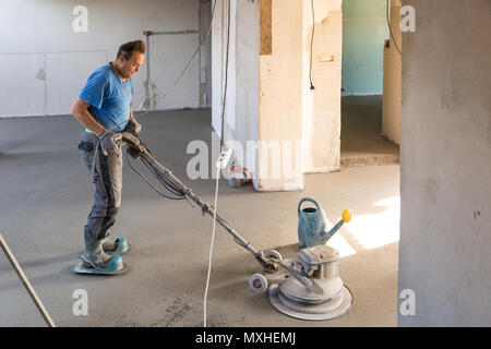 Arbeiter polieren Sand und Zement Estrich Boden. Stockfoto
