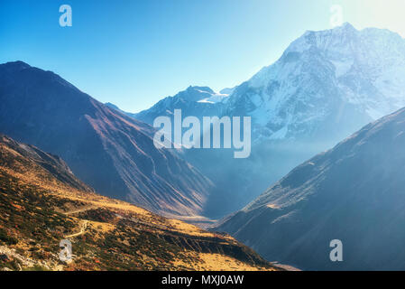 Schöne Sicht auf die Berge Tal. Landschaft mit Hügeln, Trails und schneebedeckten Berg gegen den blauen Himmel bei Sonnenaufgang in Nepal. Schneebedeckten Gipfeln des Himalay Stockfoto