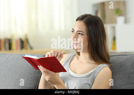 Frau denken bereit stellt in einer Agenda auf einer Couch im Wohnzimmer zu Hause sitzen zu nehmen Stockfoto