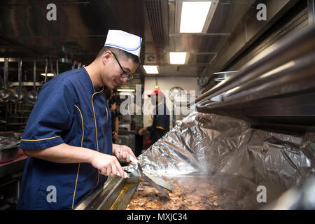 161107-N-XQ 474-016 philippinischen Meer (Nov. 7, 2016) Seemanns hing Leung Tsang Köche Schweinekoteletts in der Pantry an Bord der Ticonderoga-Klasse geführte-missile Cruiser USS Chancellorsville (CG62). Chancellorsville ist auf Patrouille im philippinischen Meer mit Carrier Strike Group (CSG 5) Unterstützung der Sicherheit und Stabilität in der Indo-Asia-Pazifik-Region. (U.S. Marine Foto von Petty Officer 2. Klasse Andrew Schneider/Freigegeben) Stockfoto