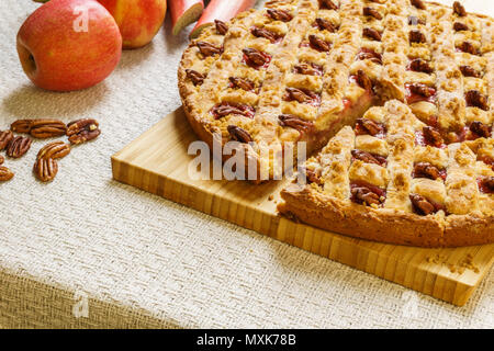 Geschnittenen Apfel und Rhabarber Kuchen mit Pecan auf einem schwarzen Fach auf eine Tabelle. Stockfoto