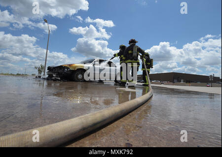 Mitglieder der Tinker Feuerwehr- und Rettungsdienste, 72nd Bauingenieur Squadron, arbeiten zusammen, um ein Fahrzeug Feuer Mai 4, 2017 zu löschen, Tinker Air Force Base, Oklahoma. William grüne Schläuche das Innere des Autos, während Kapitän David Jones mit den Schlauch wie Aaron Simpson, ganz rechts, steht - mit einer Feuer-ax unterstützt. Das privat geführte Fahrzeug entwickelt mechanische Probleme und fing Feuer in der Nähe des Oklahoma City Air Logistics Complexs' Gebäude 9001. Stockfoto