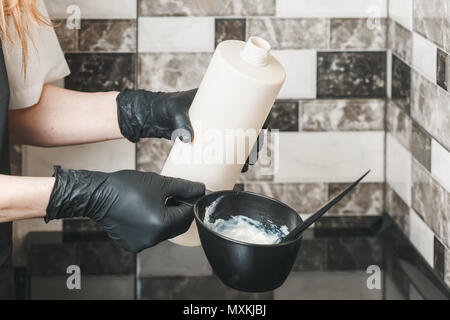 Haarstilist gießen ein Oxidationsmittel Sahne in die Schüssel Vorbereitung einer färbenden Farbstoff Stockfoto