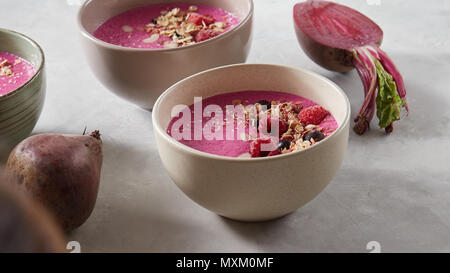 Berry Smoothie in eine Schüssel auf das Frühstück mit Beeren, Müsli und Honig auf einem Stein Hintergrund Stockfoto