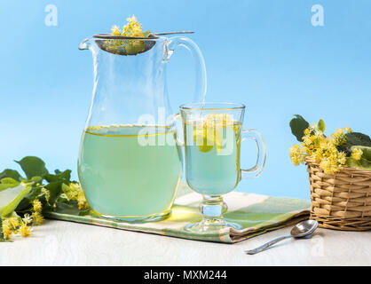 Karaffe mit Tee aus Linden Blumen auf einer Serviette und Holz Hintergrund. Stockfoto