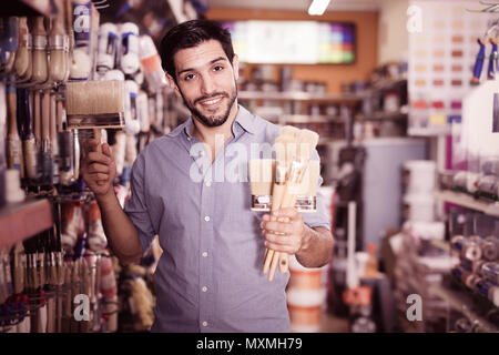 Zufrieden gewöhnlichen Mann, der in den einzelnen Racks in Farbe Speicher Auswahl von Pinseln Stockfoto