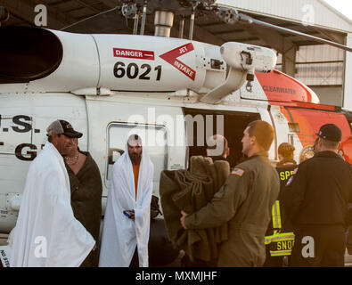 Der Küstenwache der Crew von Air Station Clearwater, Florida, fließt aus decken zu drei Personen aus einem versunkenen Schiff gerettet, etwa 35 km südwestlich von Cape San Blas, Florida, Mittwoch, November 23, 2016. Die Fischer waren zu Air Station Clearwater geflogen und mit dem EMS; keine Verletzungen zu berichten. U.S. Coast Guard Foto von Petty Officer 1st Class Michael De Nyse. Stockfoto