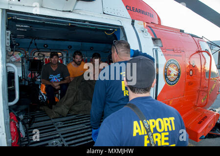 Crew Mitglieder aus St. Petersburg, Florida, Feuerwehr drei Fischer, die aus einem versunkenen Schiff ca. 35 km südwestlich von Cape San Blas, Florida, Mittwoch, November 23, 2016 gerettet wurden. Die Fischer waren, Coast Guard Air Station Clearwater von einem MH-60 Jayhawk Helikopter Crew, wo Sie mit dem EMS met geflogen, keine Verletzungen zu berichten. U.S. Coast Guard Foto von Petty Officer 1st Class Michael De Nyse. Stockfoto