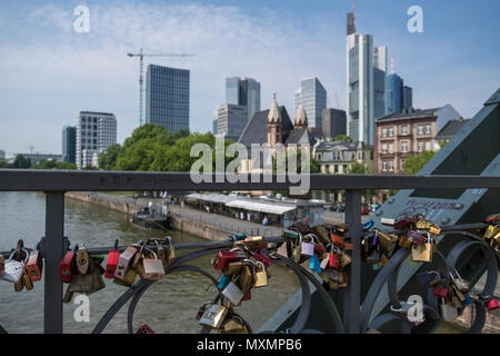 Liebe Vorhängeschlösser links auf Eiserner Steg Bridge, mit Sicht auf die City Skyline im Hintergrund, Frankfurt am Main, Hessen, Deutschland. Stockfoto