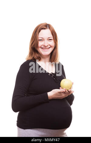 Schwangere Frau lächelnd in die Kamera, während mit einem Apfel in der Hand Stockfoto