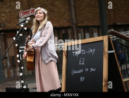 Busker Charlotte Campbell führt in Camden Market, nördlich von London, als Kate Jones, Programmdirektor bei Busk in London, schaut an. London hat erste kontaktlose Zahlung das Schema der Welt für Straßenmusikanten in Zusammenarbeit mit Technologieunternehmen iZettle gestartet. Stockfoto