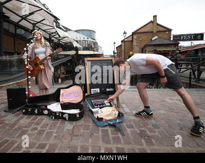 Busker Charlotte Campbell führt in Camden Market, nördlich von London, als Kate Jones, Programmdirektor bei Busk in London, schaut an. London hat erste kontaktlose Zahlung das Schema der Welt für Straßenmusikanten in Zusammenarbeit mit Technologieunternehmen iZettle gestartet. Stockfoto