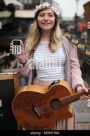 Busker Charlotte Campbell führt in Camden Market, nördlich von London, als Kate Jones, Programmdirektor bei Busk in London, schaut an. London hat erste kontaktlose Zahlung das Schema der Welt für Straßenmusikanten in Zusammenarbeit mit Technologieunternehmen iZettle gestartet. Stockfoto