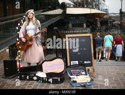 Busker Charlotte Campbell führt in Camden Market, nördlich von London, als Kate Jones, Programmdirektor bei Busk in London, schaut an. London hat erste kontaktlose Zahlung das Schema der Welt für Straßenmusikanten in Zusammenarbeit mit Technologieunternehmen iZettle gestartet. Stockfoto