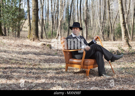 Mann allein im Wald sitzt auf einem Sessel Stockfoto