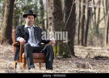 Mann allein im Wald sitzt auf einem Sessel Stockfoto