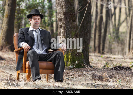 Mann allein im Wald sitzt auf einem Sessel Stockfoto