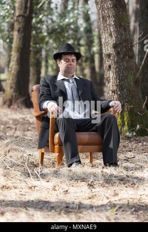 Mann allein im Wald sitzt auf einem Sessel Stockfoto