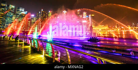 Singapur - April 26, 2018 Panorama von Spektren zeigen der tanzenden Fontänen: Licht und Wasser zeigen entlang der Promenade vor der Marina Bay Sands. Central Business District Wolkenkratzer auf Hintergrund. Stockfoto