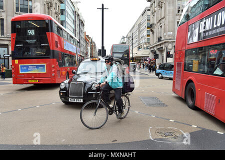 Eine Deliveroo Lieferung Reiter auf seinem Fahrrad das Oxford Circus Road Kreuzung verhandelt in Central London. Stockfoto